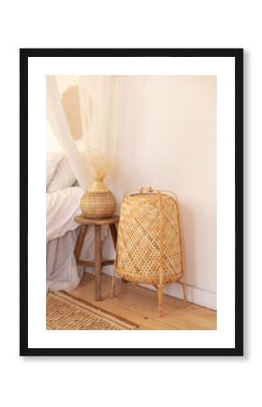 Rattan floor lamp and wooden coffee table with vase with pampas grass in bedroom interior. Large wicker lamp is on floor. Cozy decor in boho style. Concept of interior design in bohemian style