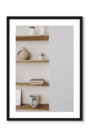 Aesthetic modern minimalist Scandinavian home interior decorations. Elegant bohemian living room with white wall, shelves with candle, picture frame, storage box, bottle, vase, fragrance