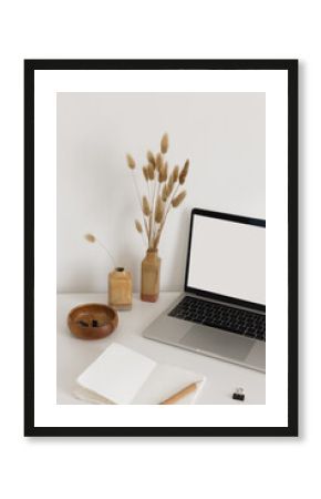 Open notebook with stationary, vases with dried flowers and laptop on the white desk. Back to school minimalistic modernt still life. Screen mock up for your text or image.