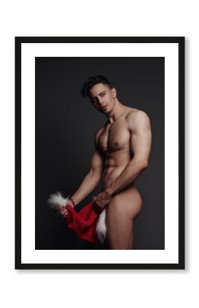 Naked handsome man covering himself with Santa hat 