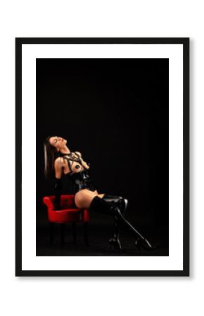 Pretty young woman sitting, in profile , wearing latex lingerie
