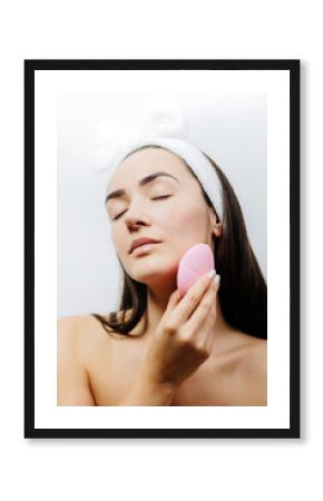 naked woman using cleansing brush for face deep cleaning . Beautiful woman clean face with cleansing brush. 