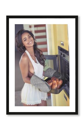I made my favourite. Cropped portrait of a sexy young woman making chicken while wearing only an apron in her kitchen at home.