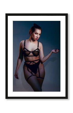 Cropped portrait plus size woman. Beautiful curvy body, seductive lady posing In underwear. Attractive oversized female In lingerie standing on dark blue studio background.
