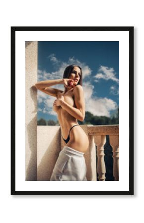 Attractive girl undresses on the balcony on a sunny day at the resort