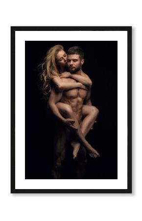 Two naked people on black background. Handsome couple in studio. Beautiful blond girl riding on fitness male model back.