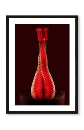 A sexy girl in black mesh tights and red patent leather high-heeled shoes is dancing in a dark room.