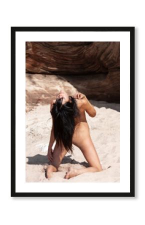Young woman posing nude on a sandy beach