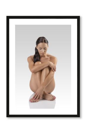 naked brunette sitting on a floor with bowed head