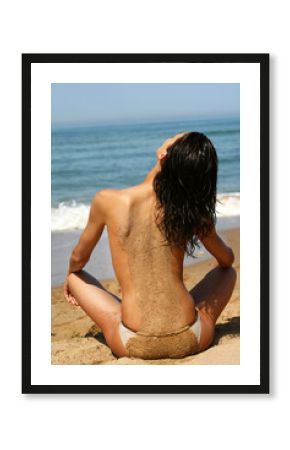 femme seins nus de dos assise sur la plage