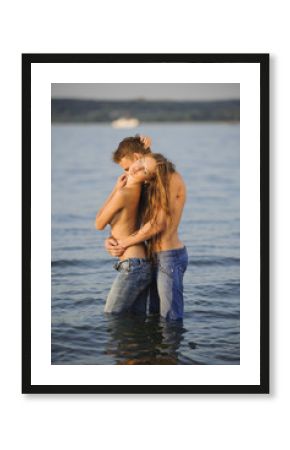 Happy passionate couple of young man and woman stand in the wate