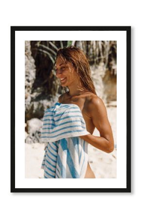 Attractive young naked woman with towel at beach.