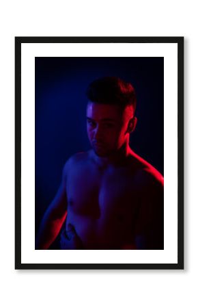 Young sexy man in a studio with blue and red lights.