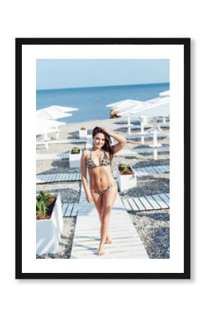 Slim brunette in swimsuit sunbathing on the beach by the sea