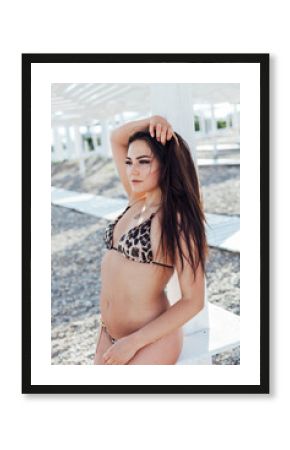 Slim brunette in swimsuit sunbathing on the beach by the sea