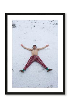 Joven alegre tumbado sobre la nieve desnudo