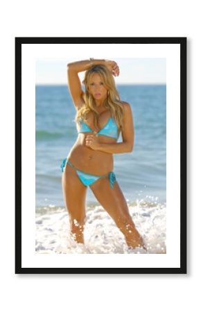 Beautiful blonde girl posing on the beach wearing blue bikini.