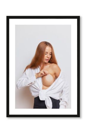 Young woman dressed in white shirt poses with one naked breast covered body colour nipple sticker, body beauty concept, copy space