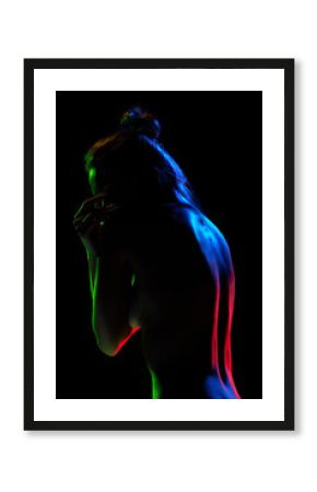 Tender, sensual, naked woman posing against black studio background in neon lights Self-care and body-positivity. Concept of female beauty, body art, aesthetics, femininity and sensuality.