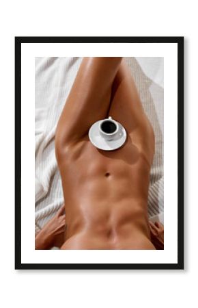 Morning coffee. Sunburned, tanned young, sexy naked woman with athletic body, breast holds cup of coffee on her belly. High fashion, glamour and style.