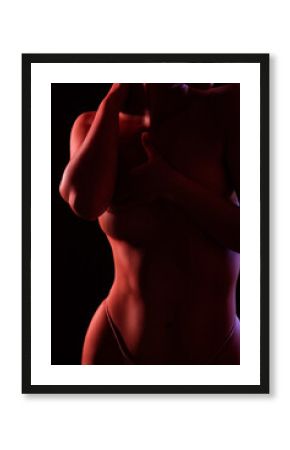 Slim sexy woman in lingerie on a dark background. Her body is illuminated with blue and red lights.