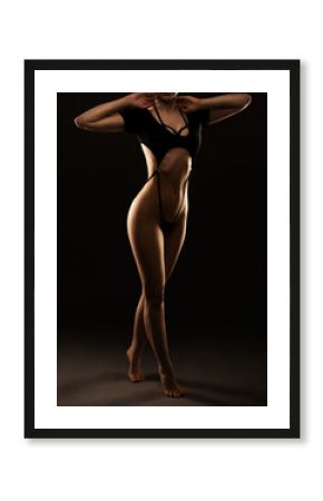 Beautiful girl body with black sexy underwear on a black background. A young sensual slender girl close up nudity.