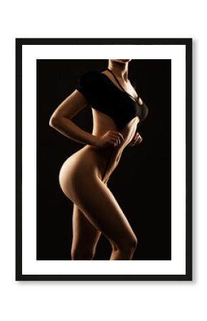 Beautiful girl body with black sexy underwear on a black background. A young sensual slender girl close up nudity.
