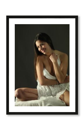 young sexy woman covering herself with white fabric cloth in low lighting 