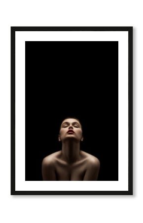 beautiful young naked woman posing sensually holding head up on black background with copy space