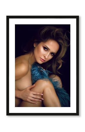 Elegant girl covers her nakedness with blue coat. Professional makeup and curly hairstyle, perfect skin and sensitive posing