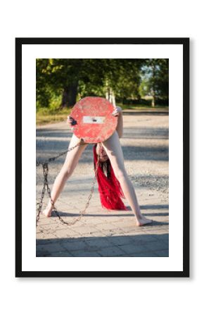 Nude beautiful woman holding STOP road sign and covering herself outdoors