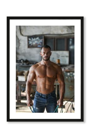 Muscled half naked man at work in an old factory.