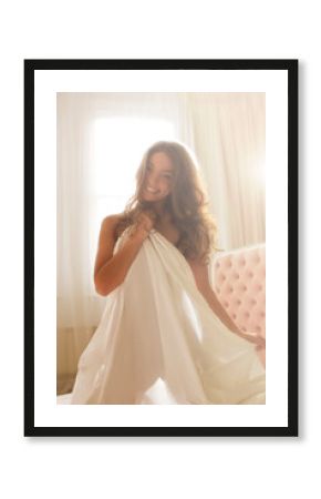 Nude woman wrapped in sheet on bed