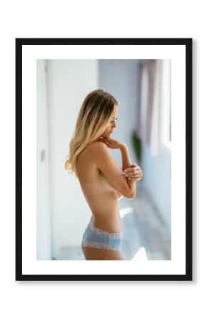 Beautiful slim topless woman wearing panties at home