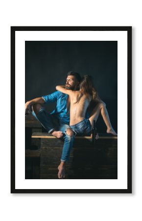 Romantic couple spending time together and enjoy the sensual moment. Sexy topless girl hugging brutal bearded macho man holding a glass with alcohol. Total jeans look style.