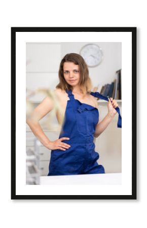 Waist-up portrait of seductive naked woman in overall standing inside office.