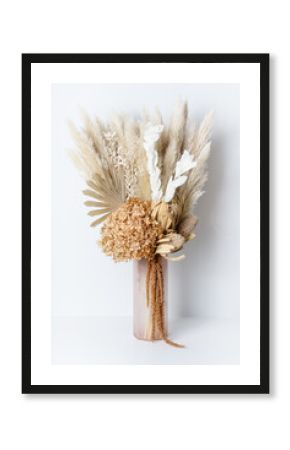 Modern dried flower arrangement in a pink vase. Including Banksia, Hydrangea, pampas grass, Palm Fronds, cream Ruscus leaves, and rust Amaranthus. Photographed on a white background