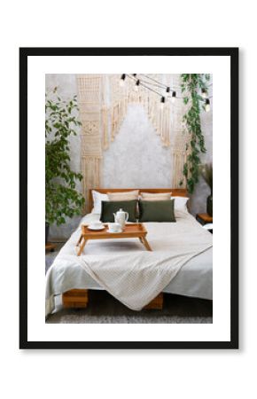 Cozy bedroom with macrame over bed and tea cup, apartment with light interior design in boho chic style