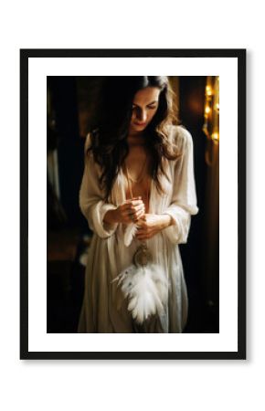 Woman with boho jewellery holding a feather in her hands close up