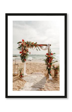 Wedding arch decorated with flowers for beach ceremony against the sea landscape. Tropical wedding ceremony in boho/ rustic style