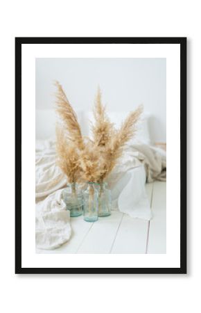 Pampas dry grass in blue vases in white bedroom