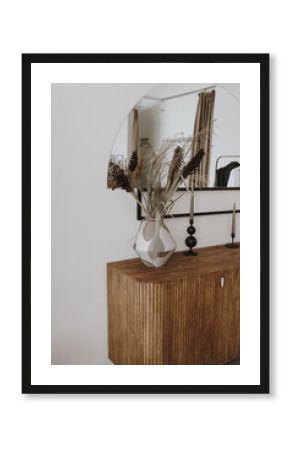 Aesthetic modern Scandinavian home interior design. Elegant bohemian living room with wooden console, mirror, candles, white walls, dried flowers bouquet, decorations