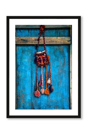 Vertical shot of a boho-style bag hanging from wooden hook against a blue background