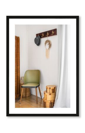 Entrance hall with white hay in atmospheric boho style. On the wall there is a carved hanger for outerwear and a man's black hat. Nice green wooden chair. Boxes on the floor for decoration.