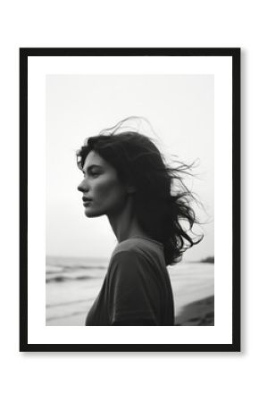 A moody black and white portrait of a free-spirited woman by the ocean.