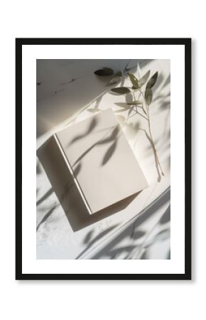 Photo of a minimalist blank journal on an elegant white table with sun rays and shadows. Top View of personal planner  Mockup notebook design.