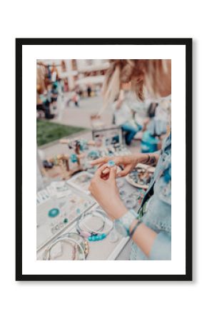  Girl looking at the colourful handmade jewelry on the local fair outside. Horizontal orientation. 