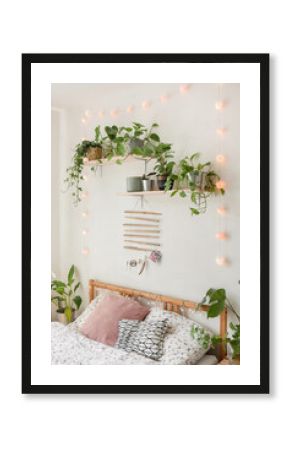 Spathiphyllum, ivy, pothos, alocasia and other plants in the bedroom for the air cleaning and better sleeping, interior plant next to the bed with small cute lighting chain