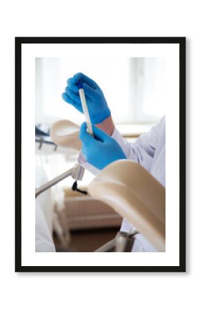 Lekarz w niebieskich rękawiczkach pobiera materiał do cytologii. 