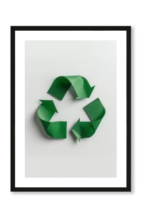 Green recycle symbol made of paper is lying on a white background, promoting environmental awareness and sustainable practices